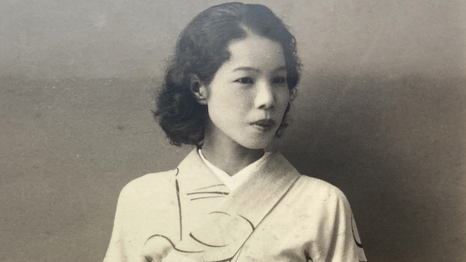 Kikuko Kanai, a Japanese women with shoulder length dark hair, in a white kimono, looking off to the side of the photo.